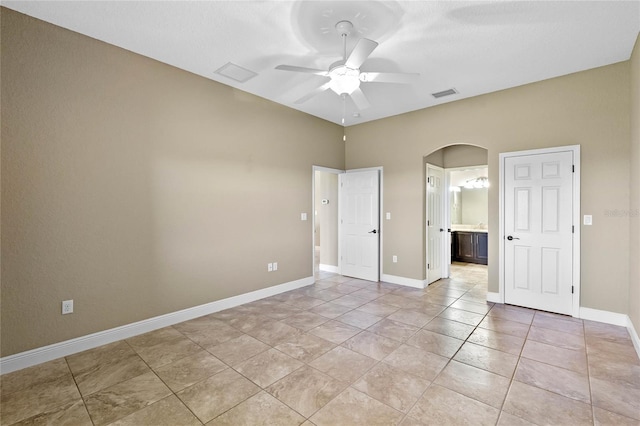 unfurnished bedroom featuring visible vents, baseboards, light tile patterned flooring, arched walkways, and ensuite bath