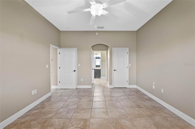 empty room with arched walkways, visible vents, baseboards, and ceiling fan