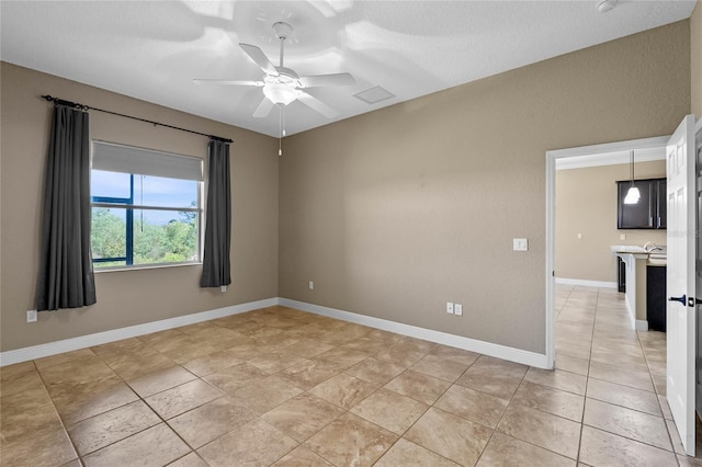 spare room featuring light tile patterned flooring, a ceiling fan, and baseboards