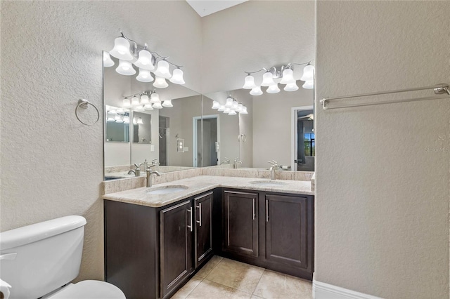 full bathroom with double vanity, tile patterned floors, toilet, and a sink