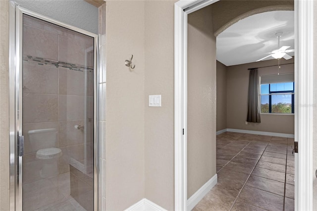 bathroom with a shower stall, baseboards, and ceiling fan