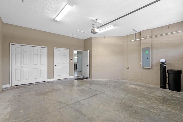 garage with concrete block wall, electric panel, and a garage door opener