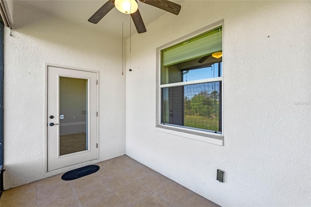 view of exterior entry featuring stucco siding and a ceiling fan