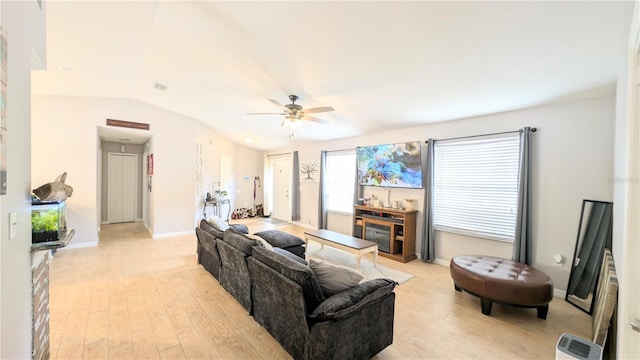 living area featuring baseboards, light wood-style flooring, a ceiling fan, and vaulted ceiling