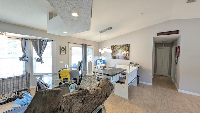 dining space with baseboards, lofted ceiling, a textured ceiling, and light wood-style flooring