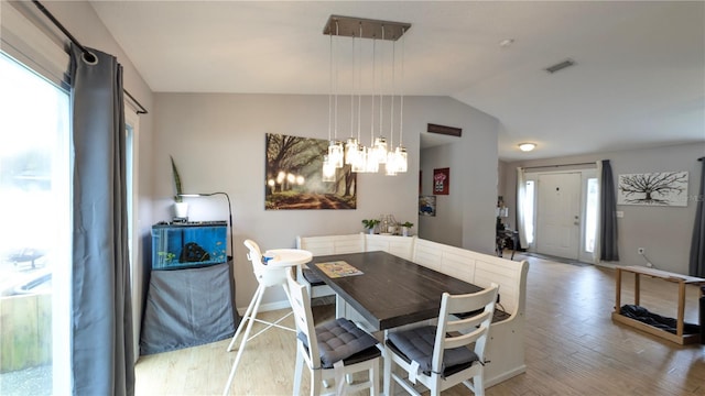 dining area featuring visible vents, baseboards, vaulted ceiling, light wood-style flooring, and a notable chandelier