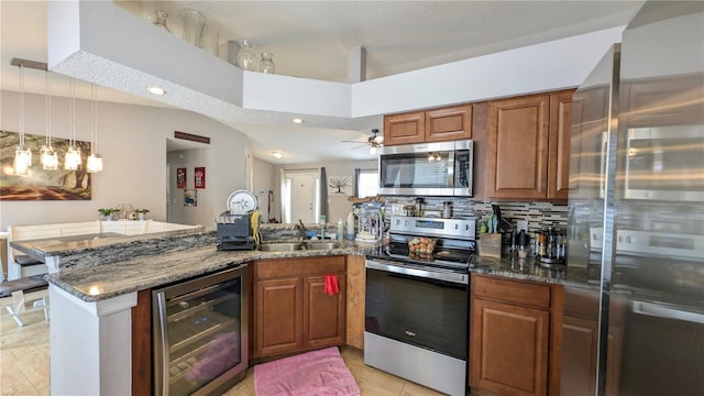 kitchen with wine cooler, dark stone countertops, a peninsula, brown cabinets, and stainless steel appliances