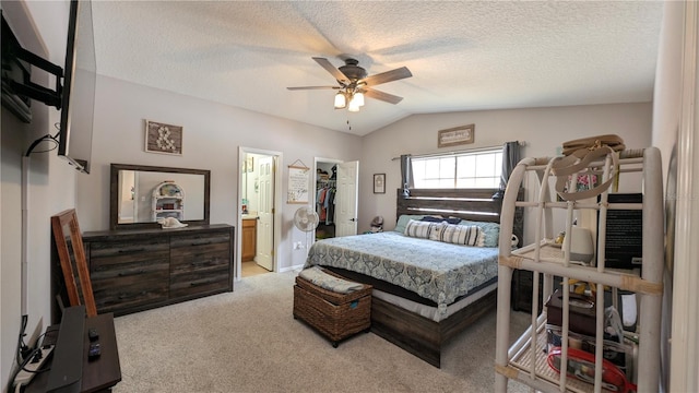 bedroom featuring light carpet, a textured ceiling, ceiling fan, a spacious closet, and vaulted ceiling