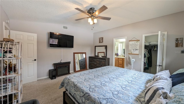 bedroom featuring visible vents, a walk in closet, vaulted ceiling, carpet flooring, and a textured ceiling