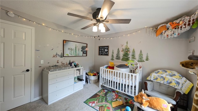 bedroom with ceiling fan, a crib, and carpet