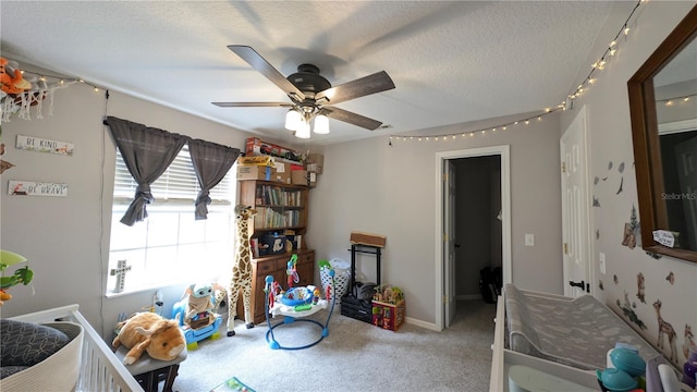 recreation room with ceiling fan, carpet, baseboards, and a textured ceiling