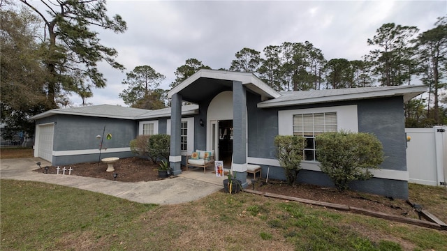 view of front of property with stucco siding, driveway, fence, a front yard, and a garage