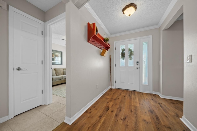 foyer with wood finished floors, baseboards, a textured ceiling, and ornamental molding