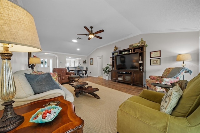 living room featuring ceiling fan, wood finished floors, ornamental molding, and vaulted ceiling