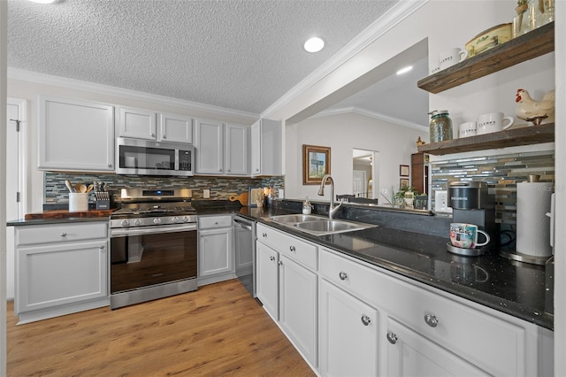 kitchen featuring a sink, open shelves, dark countertops, stainless steel appliances, and crown molding