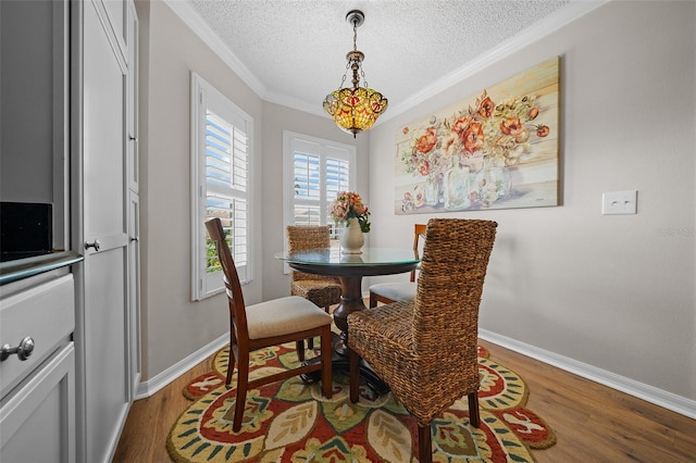 dining space with baseboards, a textured ceiling, ornamental molding, and dark wood-style flooring