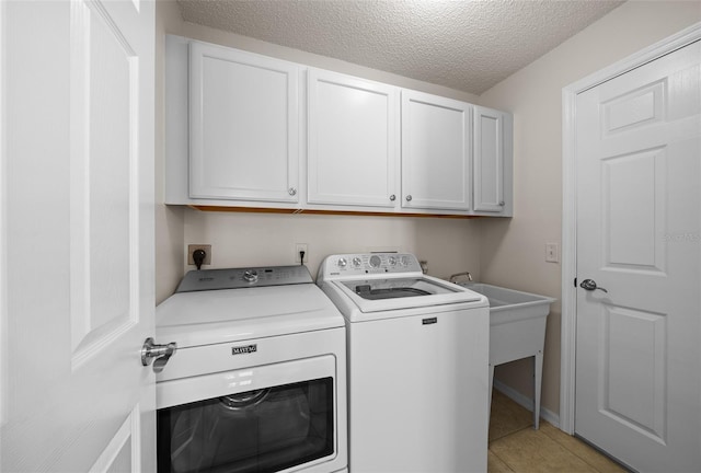 washroom featuring washing machine and clothes dryer, light tile patterned floors, cabinet space, and a textured ceiling