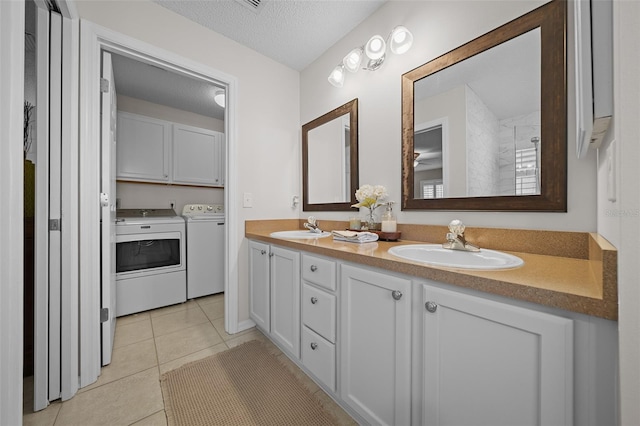 full bath with a sink, a textured ceiling, washing machine and dryer, and tile patterned floors