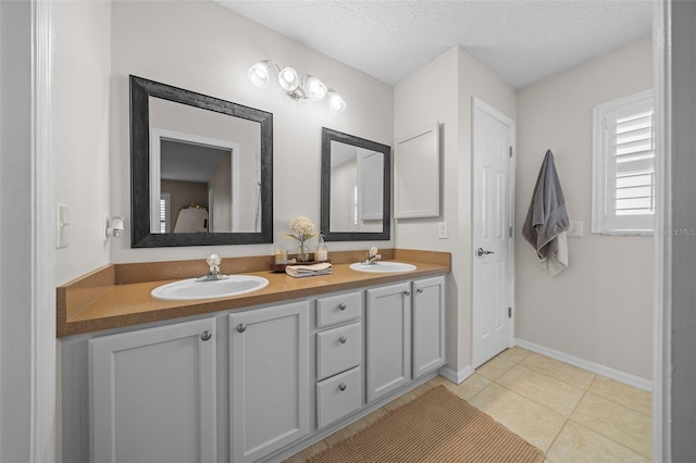 full bathroom with tile patterned flooring, double vanity, a textured ceiling, and a sink