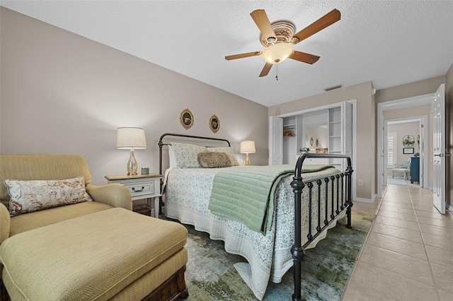 bedroom with tile patterned floors, baseboards, a textured ceiling, and a ceiling fan