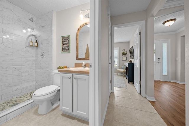 bathroom with vanity, a textured ceiling, toilet, and tiled shower