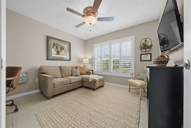 living area with light tile patterned floors, baseboards, a textured ceiling, and ceiling fan