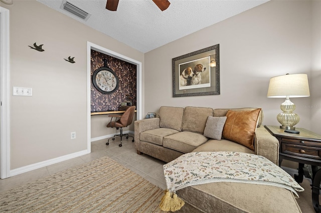 tiled living room with visible vents, baseboards, a textured ceiling, and a ceiling fan