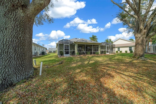 rear view of property with glass enclosure and a yard