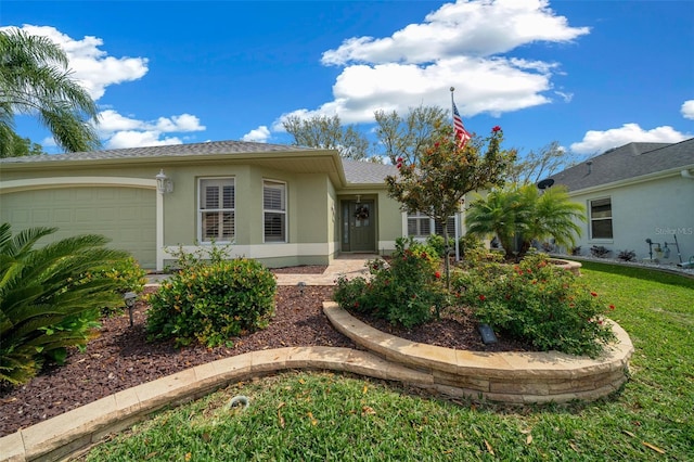 ranch-style home with a front yard, an attached garage, and stucco siding