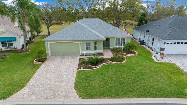 single story home featuring decorative driveway, a front lawn, an attached garage, and roof with shingles