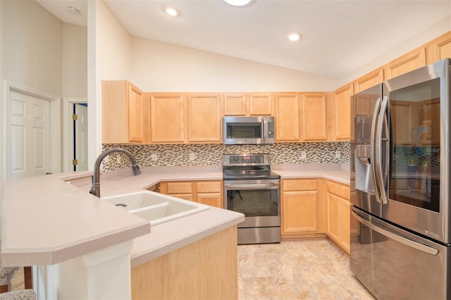 kitchen with stainless steel appliances, a peninsula, and light brown cabinetry