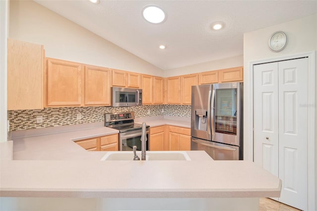 kitchen featuring light brown cabinetry, vaulted ceiling, light countertops, appliances with stainless steel finishes, and tasteful backsplash