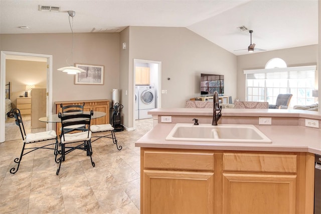 kitchen with washer / clothes dryer, a sink, vaulted ceiling, light countertops, and open floor plan