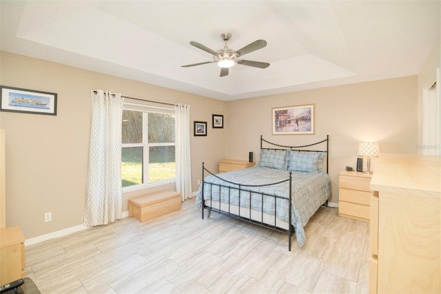 bedroom with a raised ceiling, baseboards, and ceiling fan