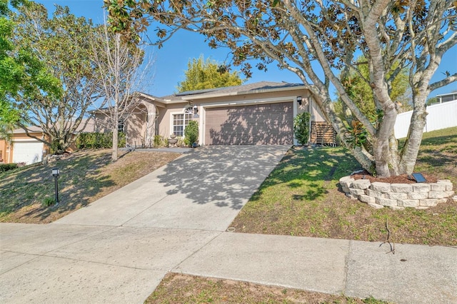 view of front of house with stucco siding, a front lawn, driveway, fence, and a garage