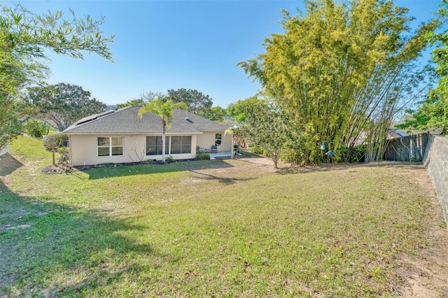 rear view of house featuring a fenced backyard, stucco siding, and a yard