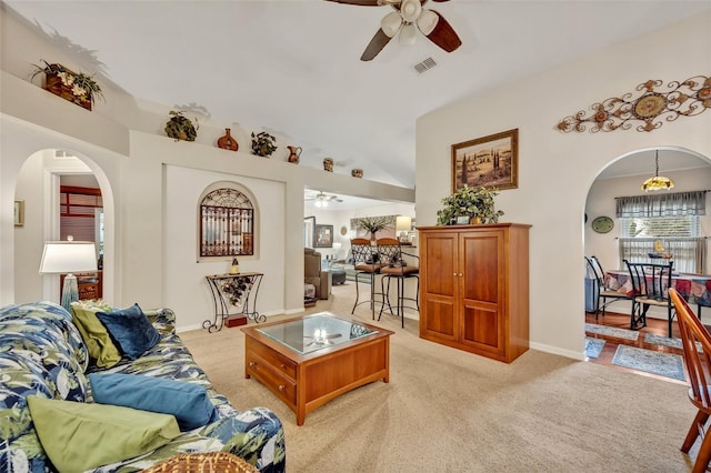 living room featuring a ceiling fan, visible vents, arched walkways, and light carpet