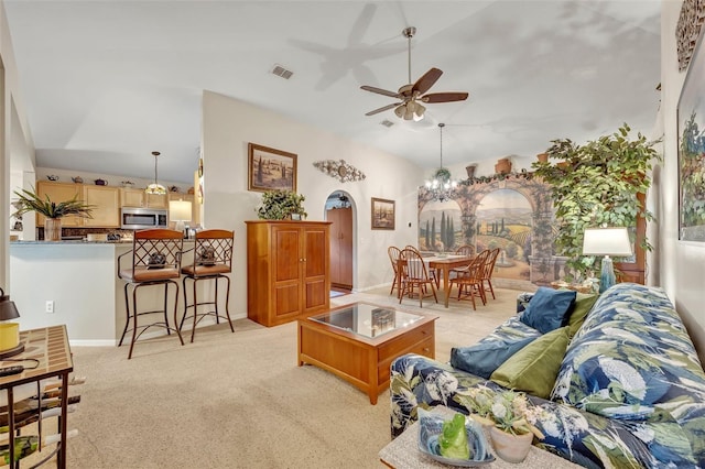 living area with visible vents, ceiling fan, vaulted ceiling, light carpet, and arched walkways