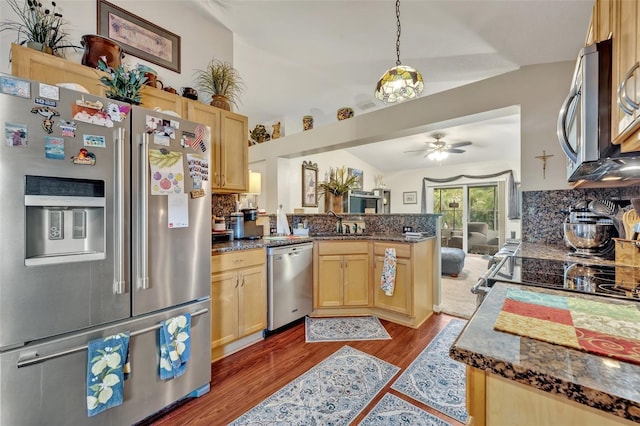 kitchen with light brown cabinets, backsplash, wood finished floors, stainless steel appliances, and a peninsula