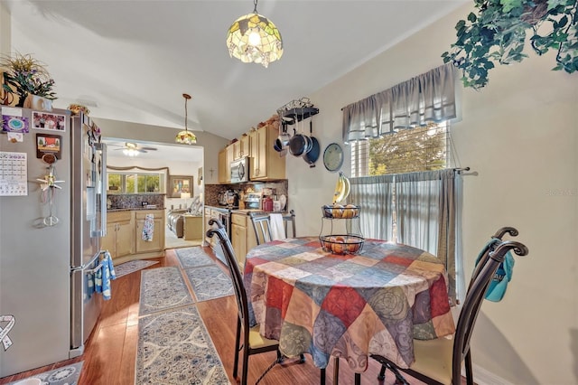 dining room featuring a ceiling fan, lofted ceiling, a healthy amount of sunlight, and light wood finished floors