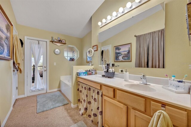 full bathroom with a garden tub, a sink, double vanity, baseboards, and vaulted ceiling