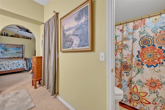 corridor with baseboards, arched walkways, carpet floors, and a textured ceiling