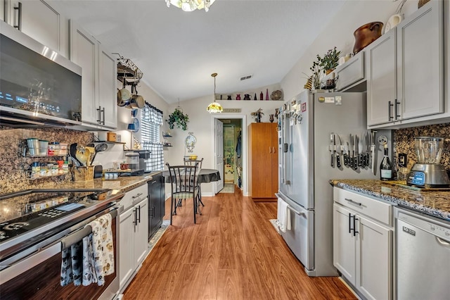 257 Winding Cove Ave, Apopka, FL 32703 - kitchen with lofted ceiling, stainless steel appliances, visible vents, decorative backsplash, and light wood-style floors