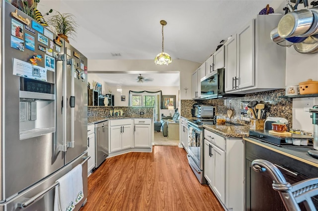 257 Winding Cove Ave, Apopka, FL 32703 - kitchen with light wood finished floors, stone counters, stainless steel appliances, white cabinets, and backsplash