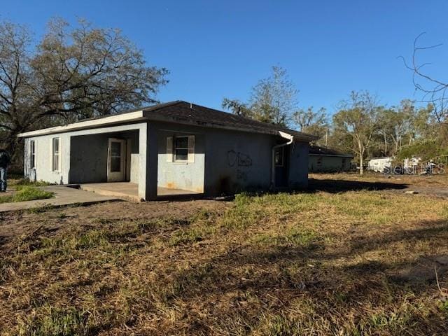 back of property with stucco siding and a patio