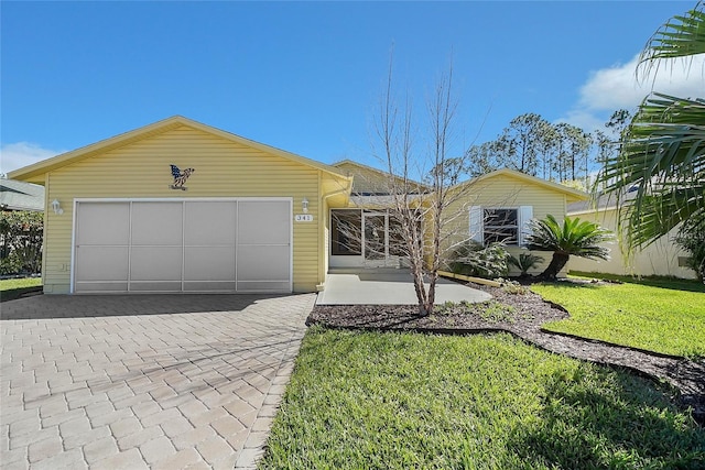 view of front facade with a front yard, decorative driveway, and a garage