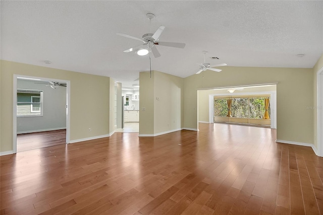 spare room with baseboards, a textured ceiling, wood finished floors, and vaulted ceiling