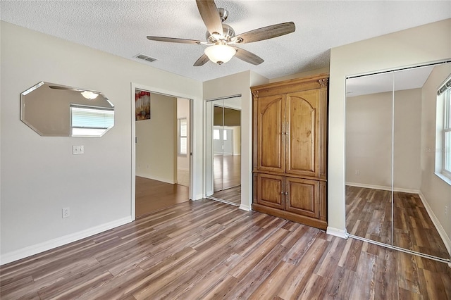 unfurnished bedroom with visible vents, light wood-style flooring, a ceiling fan, a textured ceiling, and baseboards