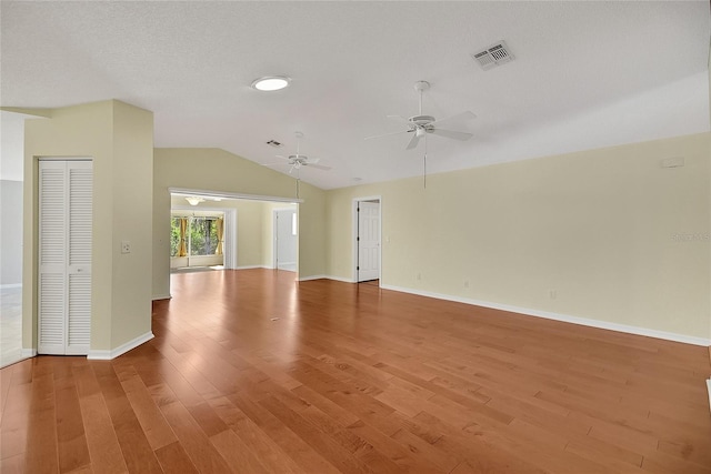 unfurnished room featuring baseboards, visible vents, light wood-style flooring, ceiling fan, and vaulted ceiling