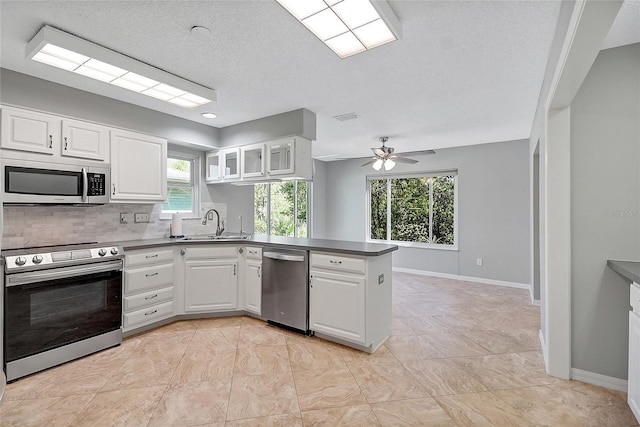 kitchen featuring a sink, appliances with stainless steel finishes, a peninsula, and white cabinets